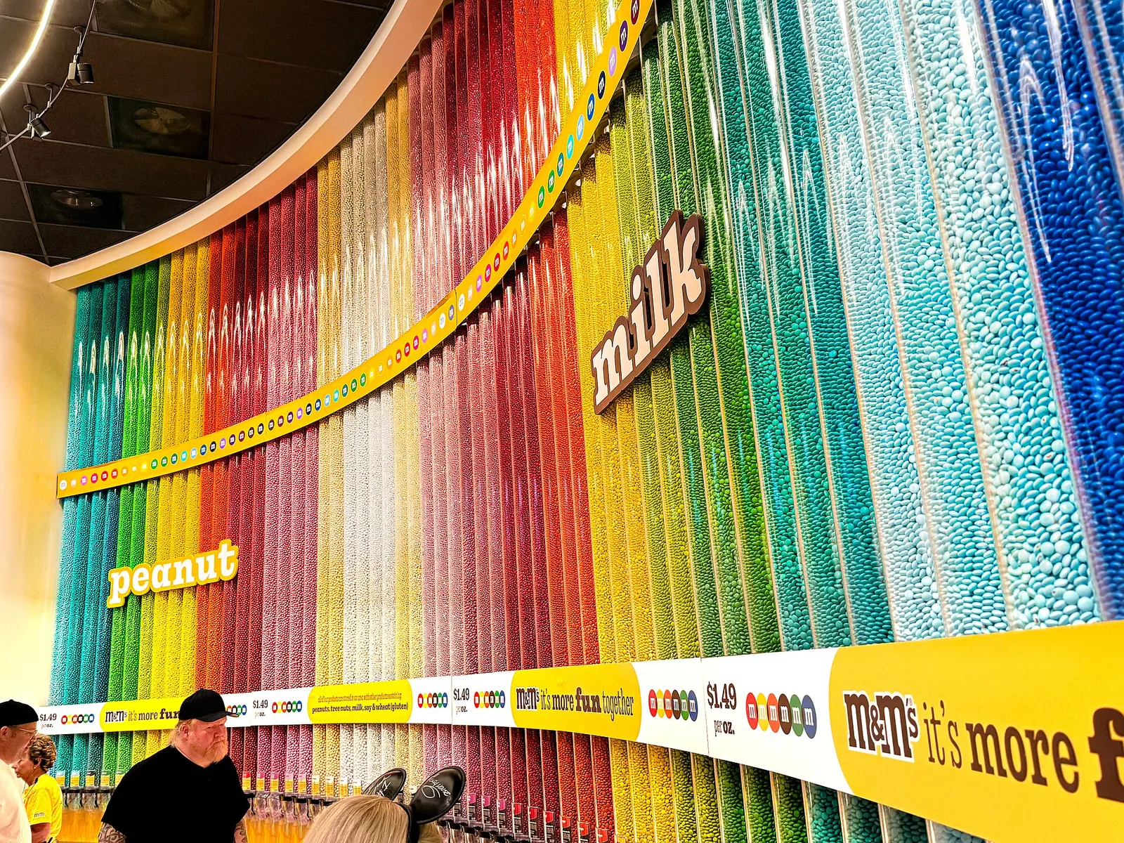 Parede de tubos de M&M's separados por cor numa loja M&M's World.