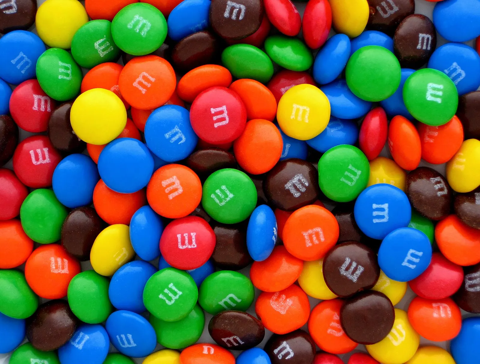 Pilha de M&M's de todas as cores, vista de perto.